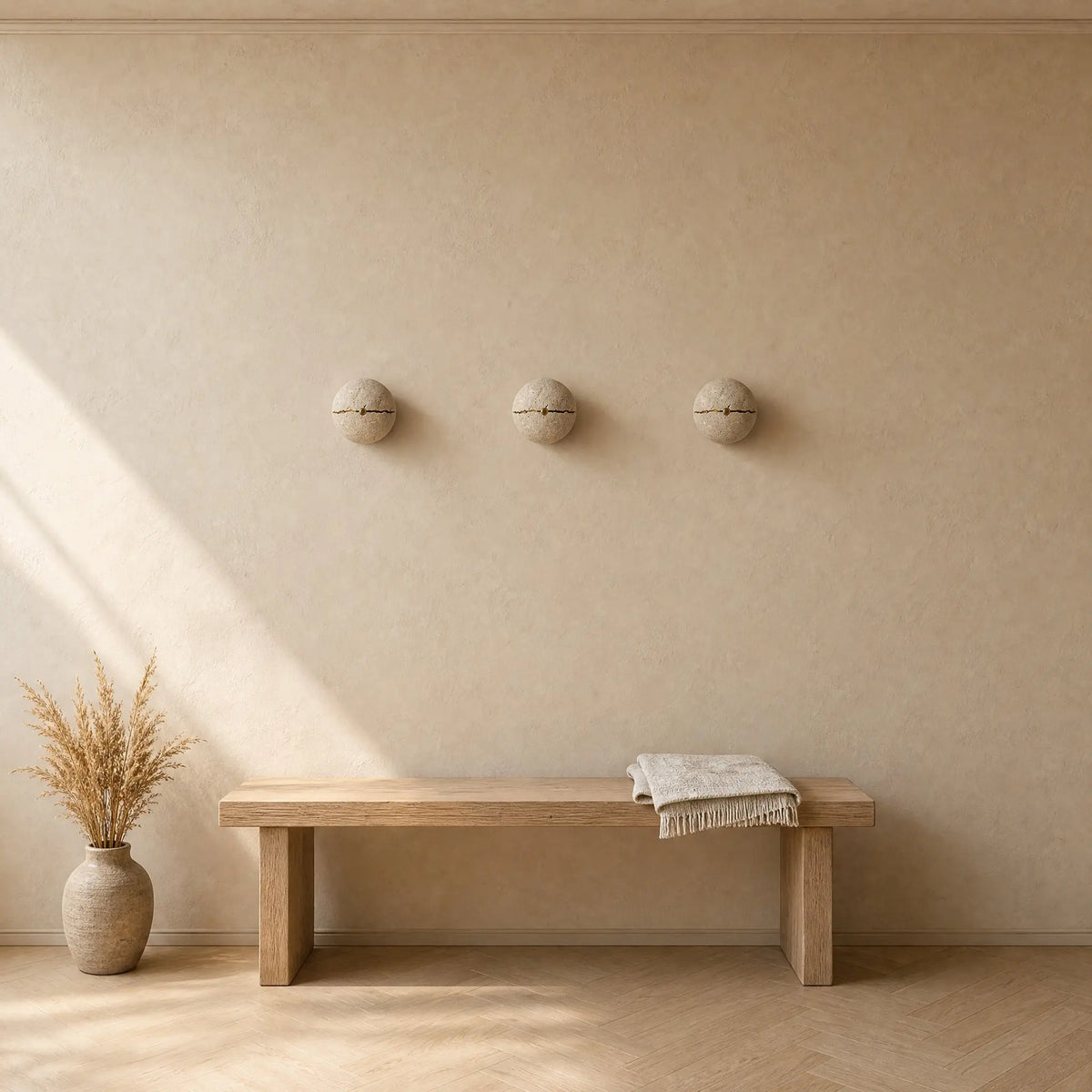 Trois appliques murales en pierre alignées au-dessus d'un banc de chêne dans une entrée, lumière naturelle | Delvanie