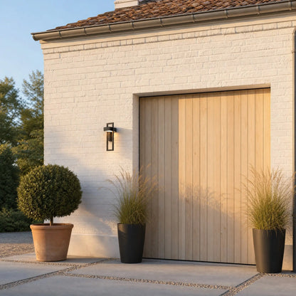 Éclairage extérieur mural Fialdo sur une façade de brique blanche, près d'une porte de garage en bois