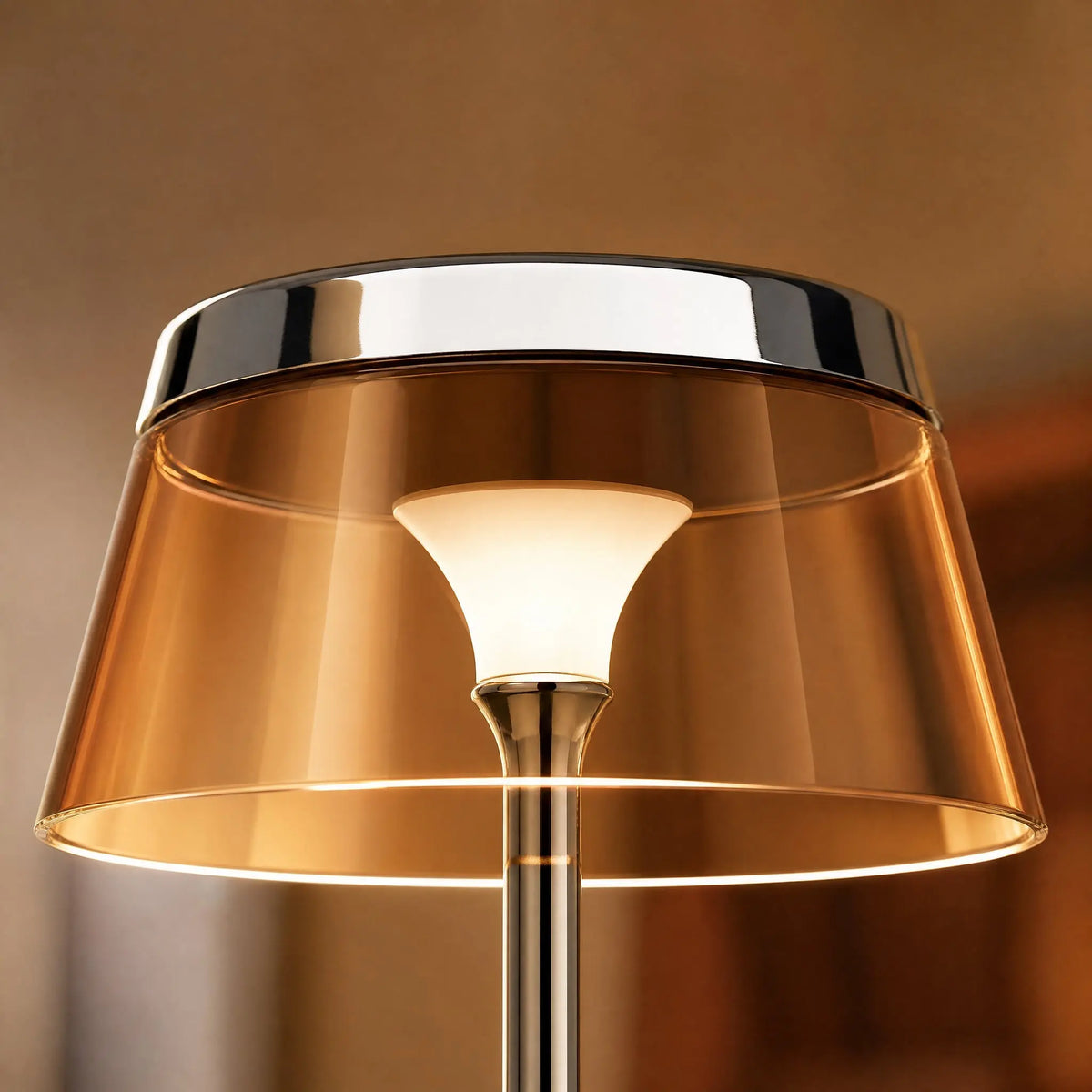 Détail de la couronne chromée et de l'abat-jour ambré traversé par la lumière de la lampe Sévali | Delvanie