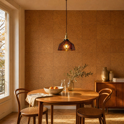 Lampe vitrail Mosaira allumée au-dessus d'une table ronde en teck, mur de liège naturel | Delvanie