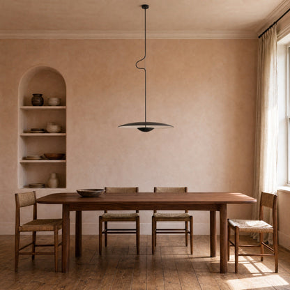 Suspension noire au-dessus d'une table de noyer dans une salle à manger aux murs ocre | Delvanie
